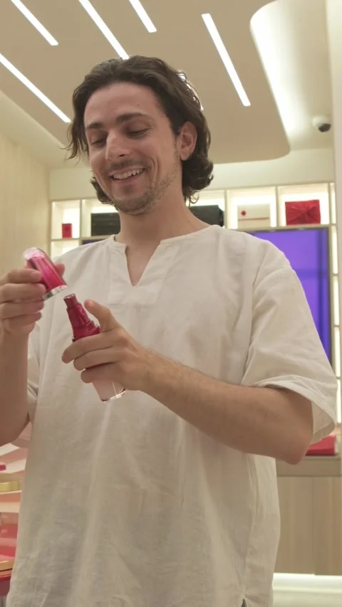 Smiling man testing perfume spray in cosmetics store Stock Footage 335191866