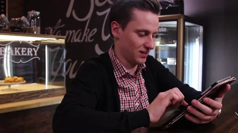 Smiling man typing text on a tablet PC at cafe 動画素材 61217101