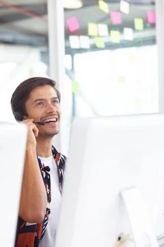 Smiling man using headset while working at office desk with computer, copy space Foto stock