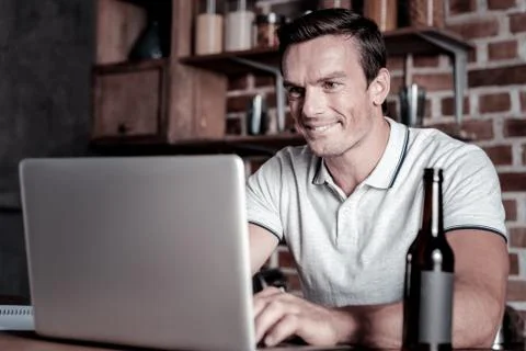 Smiling man using laptop and drinking deer Stock Photos