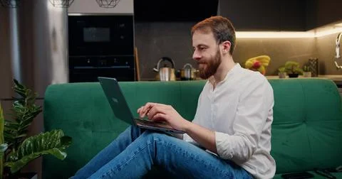 Smiling man using laptop checking email news or searching for friends in 写真素材