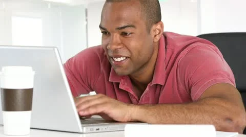 Smiling man using laptop at desk Stock Footage 11963070