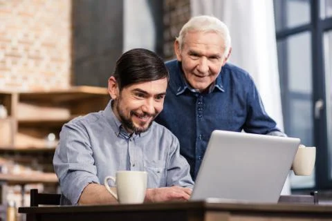 Smiling man using laptop with his aged father 스톡 사진