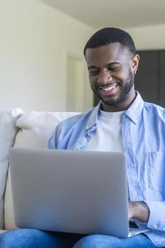 Smiling man using a laptop at home, remote work and online study, relaxed y.. 스톡 사진