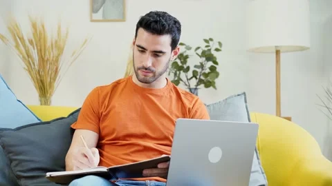 Smiling man using laptop in living room Stock Footage 228949123