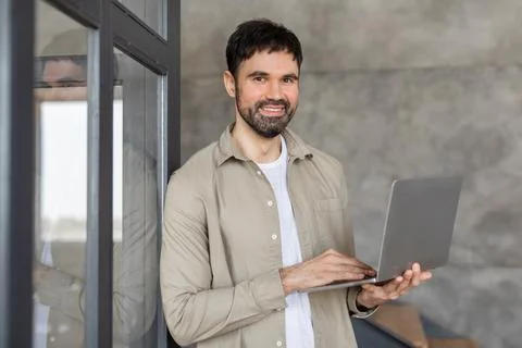 Smiling Man Using Laptop in Modern Office Building 스톡 사진