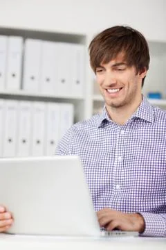 Smiling man using laptop in office Stock Photos