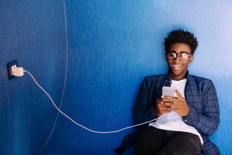 Smiling man using mobile phone while sitting in library Stockfoto's