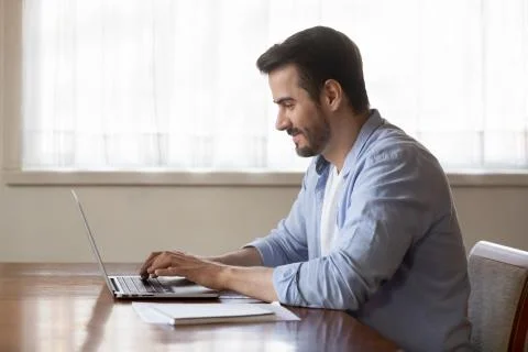 Smiling man using modern laptop typing message 스톡 사진