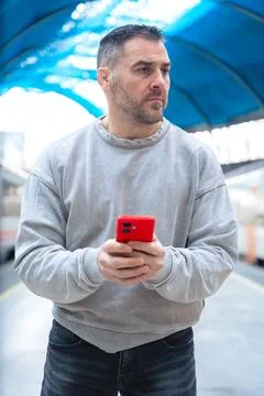 Smiling Man Using Red Smartphone at Train Station.Vertical Stock Photos