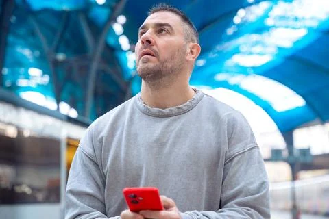 Smiling Man Using Red Smartphone at Train Station Stock Photos