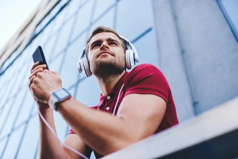 Smiling man using smartphone and headphones listening to song Foto stock