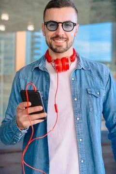 Smiling man using smartphone and holding coffee cup in modern urban setting Stock Photos