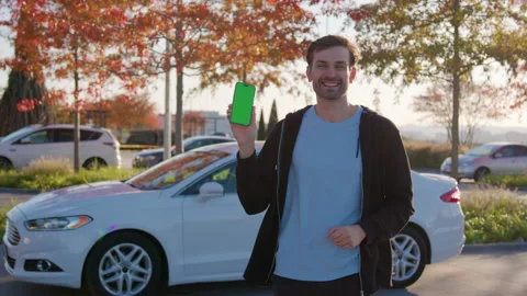 Smiling man using smartphone in a carsharing parking area, surrounded by Stock Footage 315533092