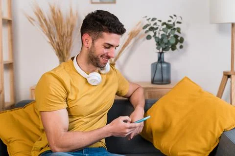Smiling man using smartphone at home Stock Photos
