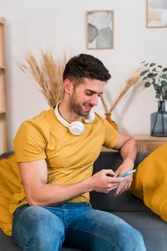 Smiling man using smartphone at home Stock Photos