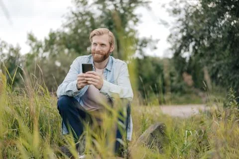 Smiling man using smartphone in nature Stock Photos