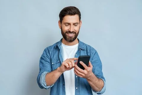 Smiling man using smartphone standing isolated on blue background copy space Stock Photos