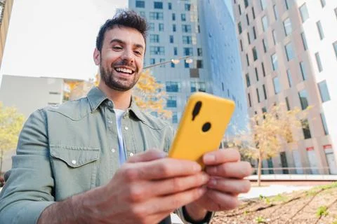 Smiling man using smartphone while enjoying a sunny day outdoors with a Stock Photos