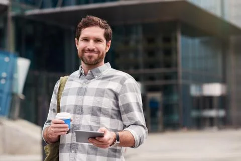 Smiling man using a tablet while walking in the city Stock Photos