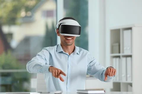 Smiling man using virtual reality headset in office Stock Photos