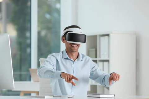 Smiling man using virtual reality headset in office Stock Photos