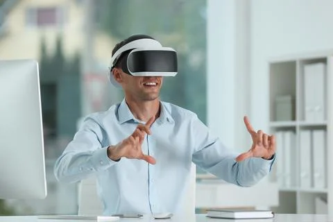 Smiling man using virtual reality headset in office Stock Photos