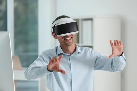 Smiling man using virtual reality headset in office Stock Photos