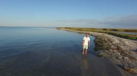 Smiling man is walking along the surf line Stock Footage 68323824