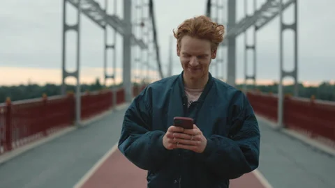 Smiling man walking on bridge with smartphone in hands Stock-Footage 162618524