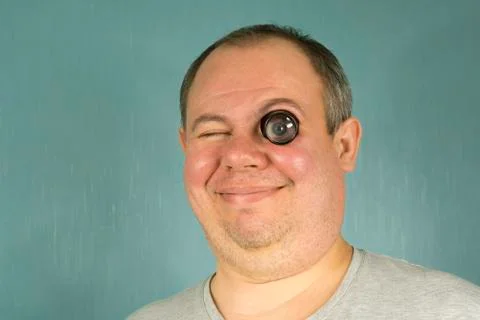 Smiling man with a watchmaker's magnifier, inserted into the eye, not to hold Stockfoto's