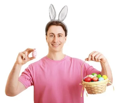 Smiling man wearing Easter bunny ears holds a basket of colorful eggs and p.. Stock Photos