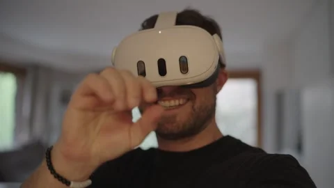 Smiling man wearing a vr headset, interacting with a virtual world and showing Stock Footage 335203580