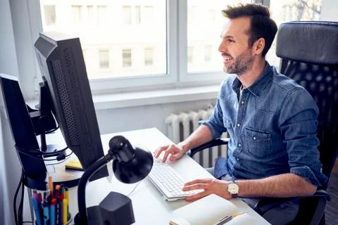 Smiling man working on computer at desk in office Foto stock