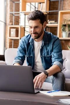 Smiling man working on laptop, checking email, writing message in social network Stock Photos