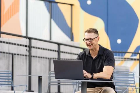 Smiling man working on laptop in front of colorful background Stock Photos
