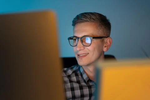 Smiling Man Working Late On Computer In Office Environment Foto stock