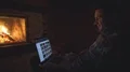 The smiling man works on laptop near the fireplace 4k or 4k+ Resolution