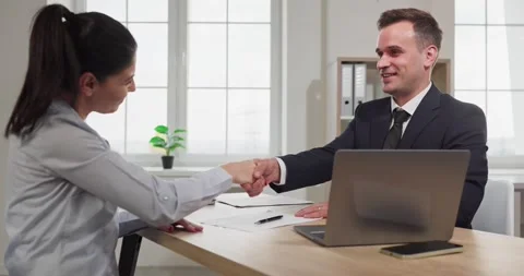 Smiling manager and client handshake across desk after signing paperwork Stock Footage 325980029