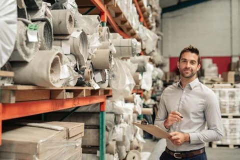 Smiling manager doing inventory on a warehouse floor Stock Photos