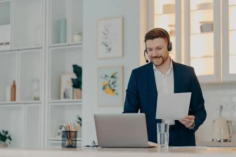 Smiling manager holding paper while typing on laptop Stock-Fotos