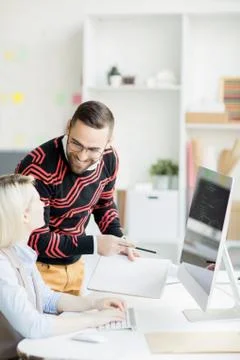 Smiling manager inspecting work of coder Stock Photos