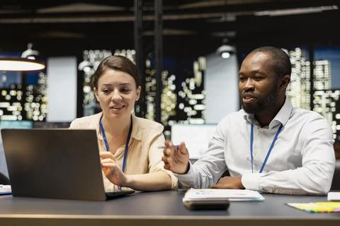 Smiling manager in office evaluating staff performance with laptop, pleased Stock Photos