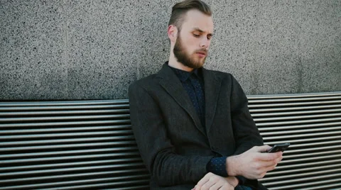 Smiling manager sitting on a bench and phoning Stock Footage 61858370