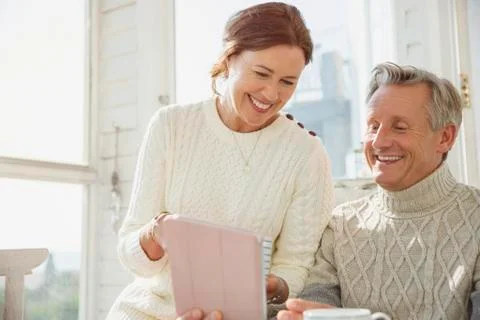 Smiling mature couple using digital tablet on sunny porch Fotos Stock
