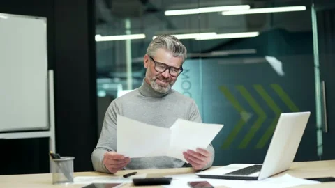 Smiling mature gray haired bearded businessman looking through business papers a Stock Footage 232581592