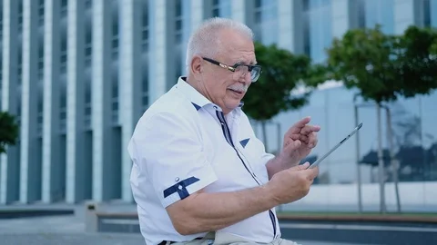 Smiling mature man sits with tablet against office building Stock Footage 115884496
