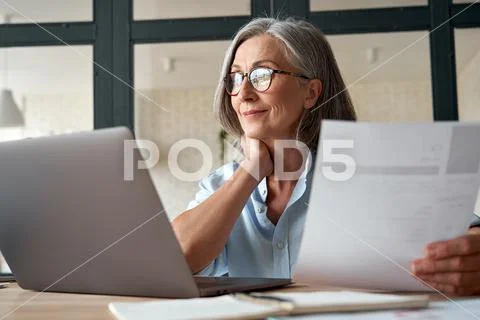 Smiling mature middle aged business woman holding cv searching job online. Stock Photos