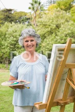 Smiling mature woman painting on canvas Stock Photos