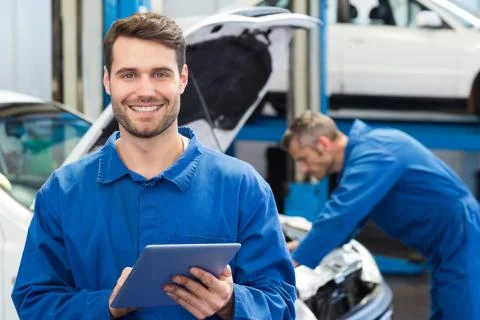 Smiling mechanic using a tablet pc Stock Photos